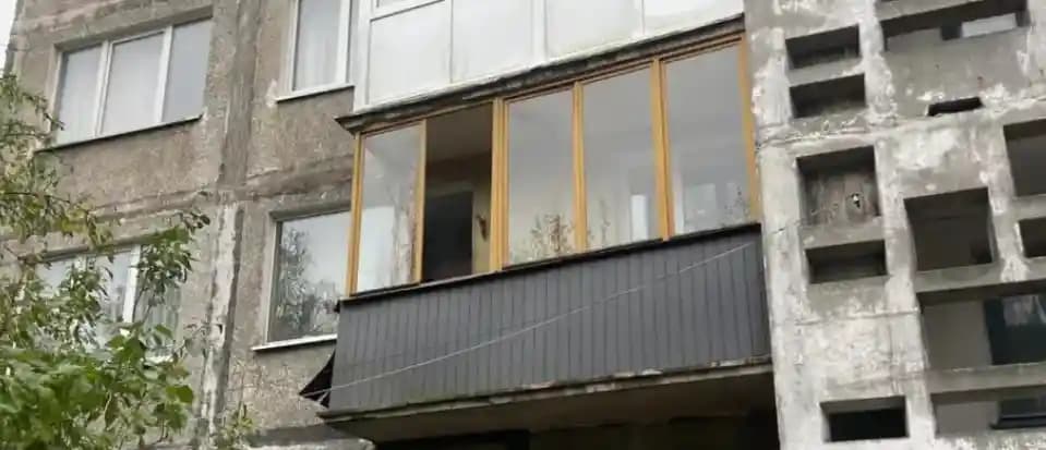 До замены: балкон с коричневыми оконными рамами и тёмной наружной обшивкой в Калининграде